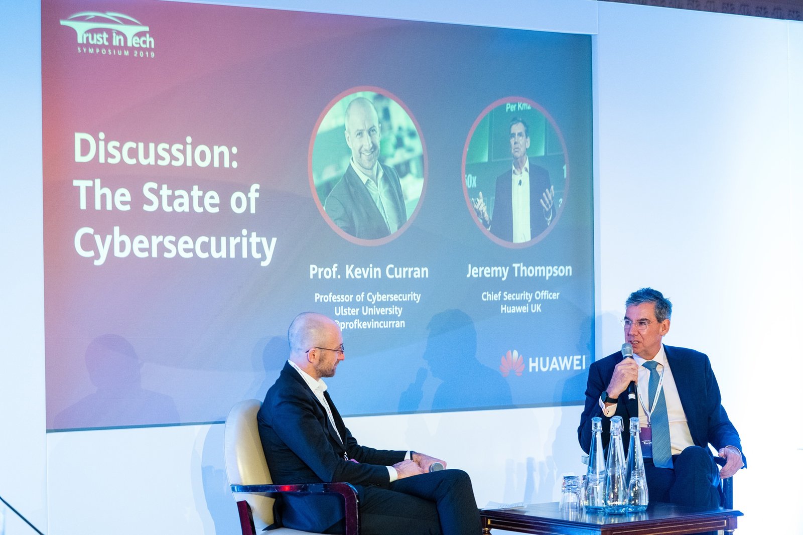 Two men are seated on a stage with a screen behind them displaying "Discussion: The State of Cybersecurity." The backdrop shows names and titles: Prof. Kevin Curran and Jeremy Thompson, along with the Huawei logo. James Gifford-Mead Photography - Event Photographer London