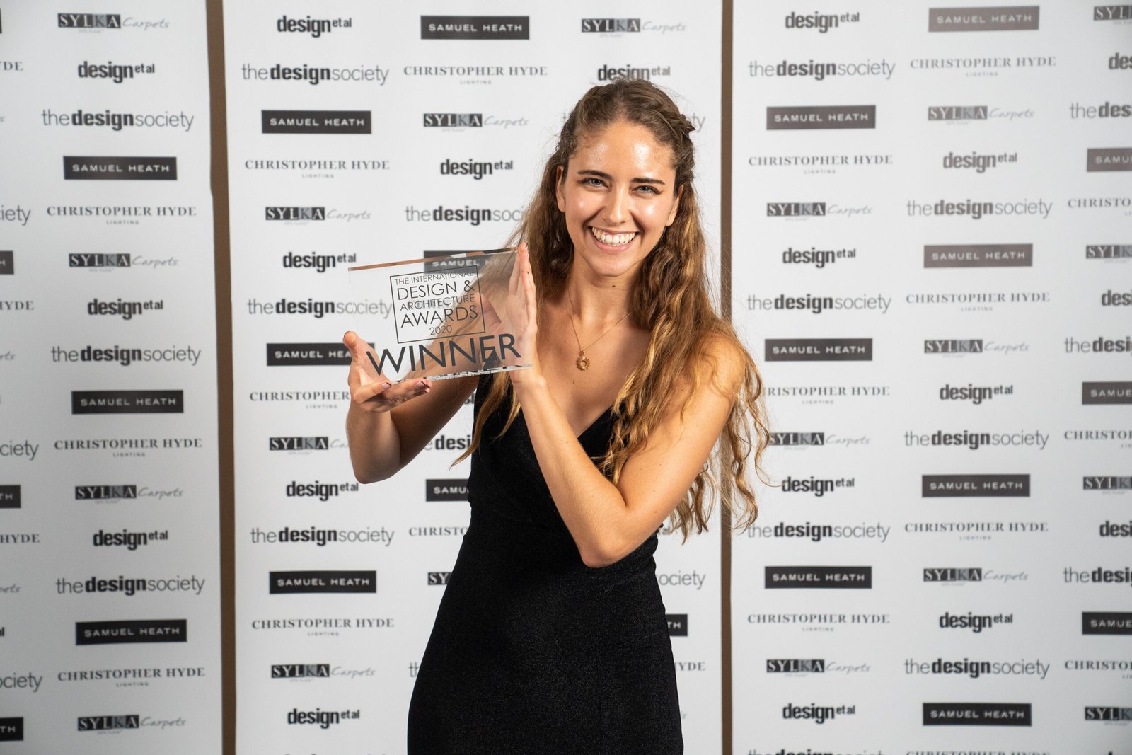 A woman in a black dress smiles and holds a 