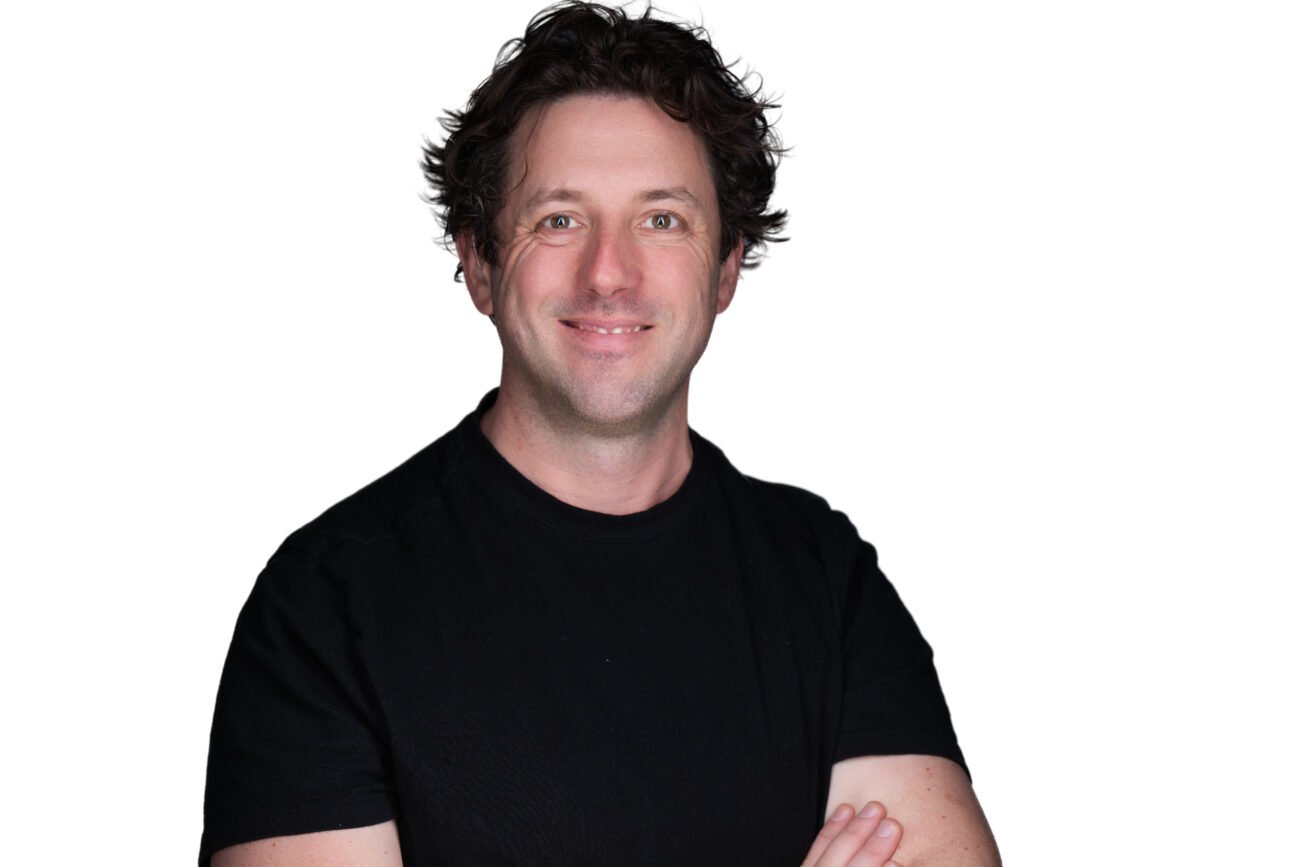 Smiling person in black shirt, white background.