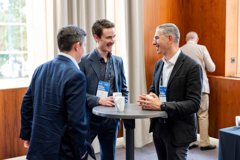 Three men talking at a conference table.