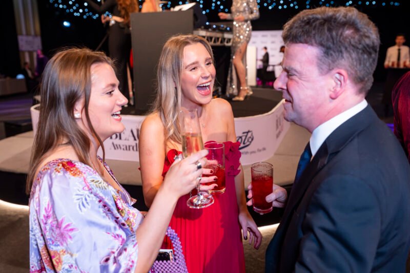 People laughing and toasting at an awards event.