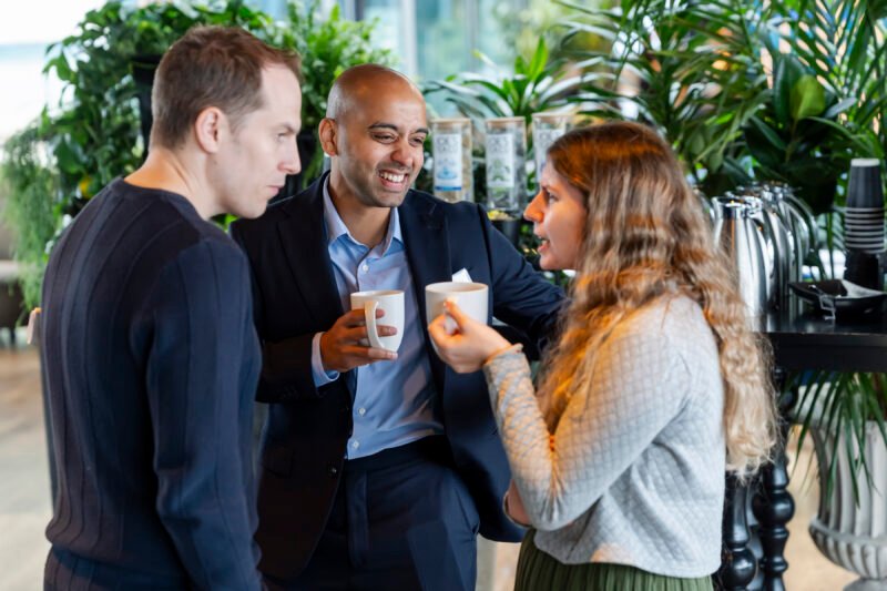 Three people chatting over coffee in a cafe.