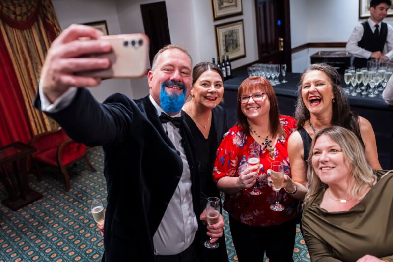 Group celebration with drinks at an event selfie.