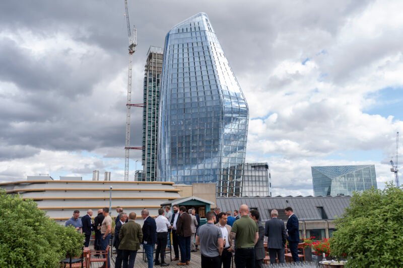 People on rooftop with modern glass buildings.