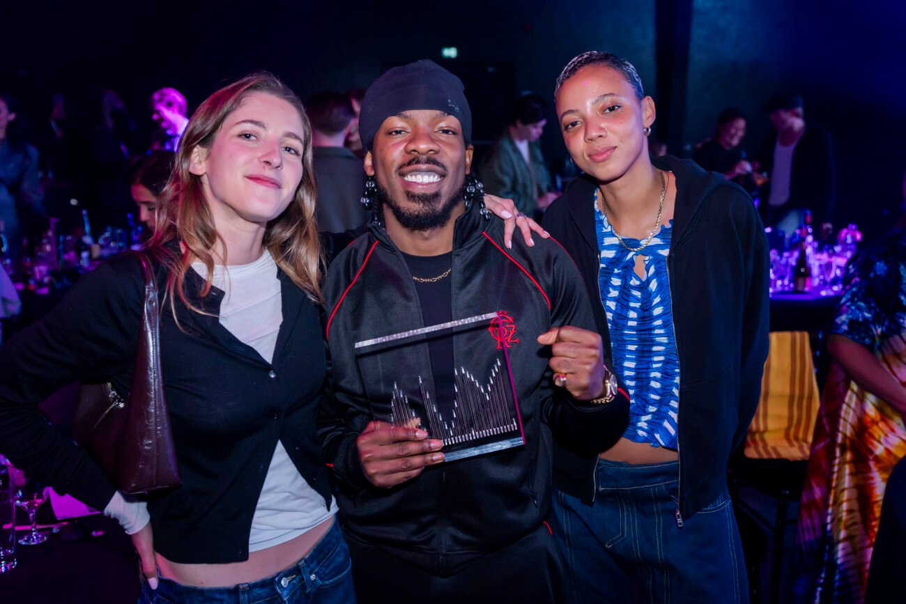 Three people celebrating at an event with award.