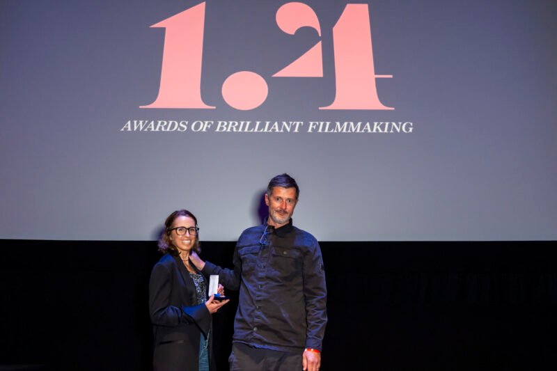 Two people at film awards ceremony on stage.