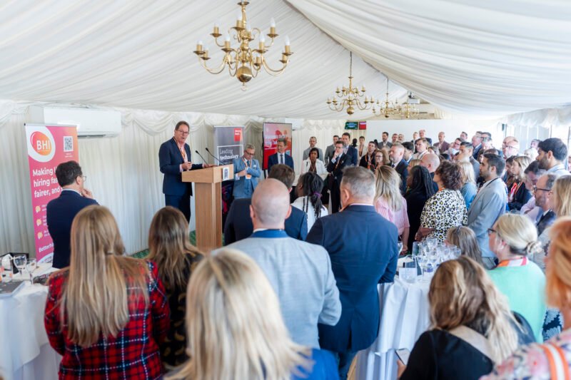 Speaker addressing audience at corporate event in marquee.